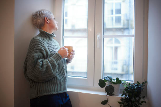 istock Woman having cup of coffee looking at the window outside 1299172247