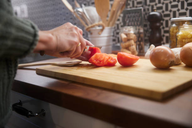 istock Senior woman cutting vegetables tomatoes in the kitchen with husband 1299172467