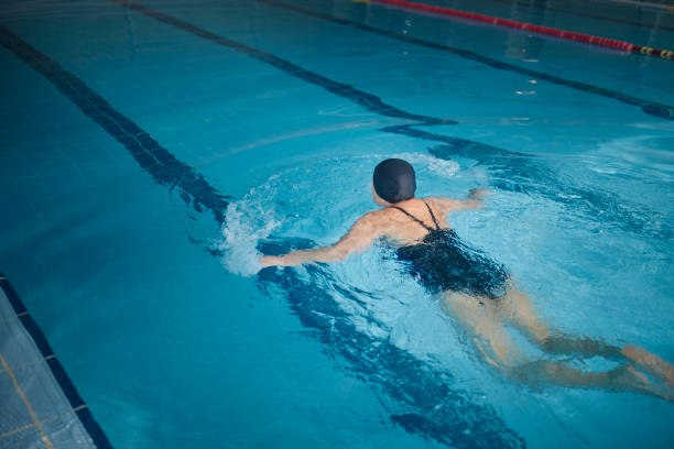 istock Active senior woman swimming breaststroke in indoor pool 1299173393