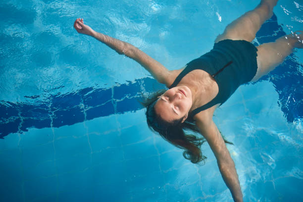 istock Young woman floating on indoor pool with hair free 1299174500