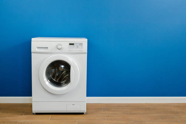 istock Clothes washing machine in laundry room interior on blue wall 1299174503