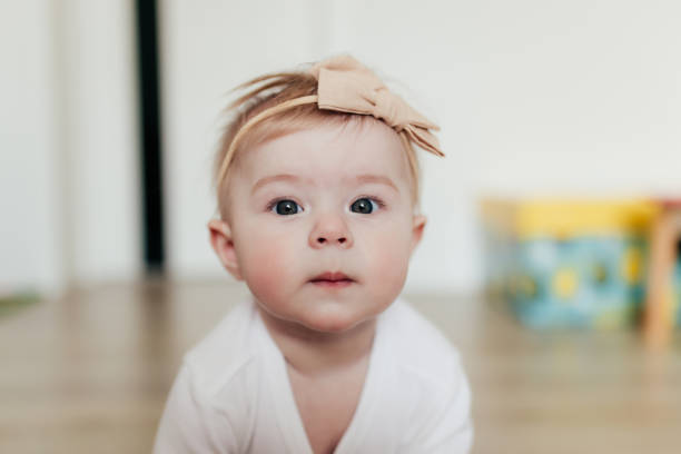 istock Little baby girl with bow looking at camera. Blurred background 1299175668