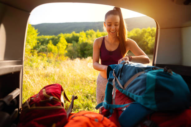 istock Smiling woman taking her backpack out of the car trunk 1299175705