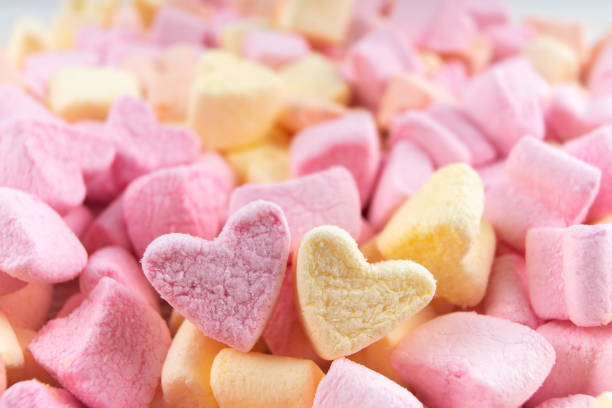 istock yellow and pink heart shape marshmallows food background. 1299176590