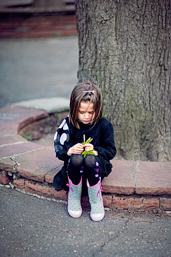 Portrait of sad girl holding green leaf
