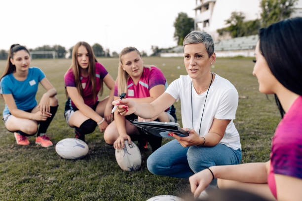 istock Female rugby coach making a play strategy with her team 1299180758