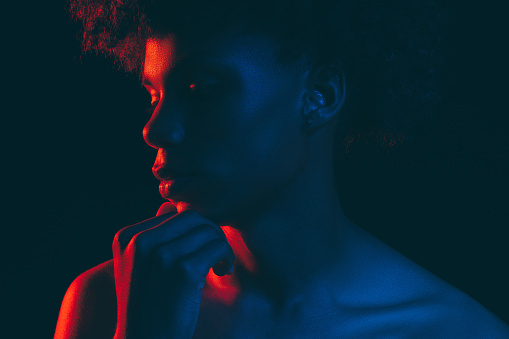 Black man silhouette. Neon light portrait. Thoughtful african male in blue red glow isolated on dark. Fashion model. Masculine power. Aesthetic cosmetology