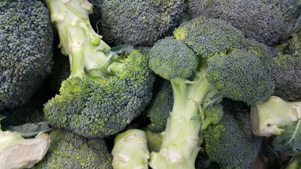 Green fresh broccoli pile placed in market for sale. Green fresh broccoli pile placed in market for sale. A Close up top view brokoli stock pictures, royalty-free photos & images