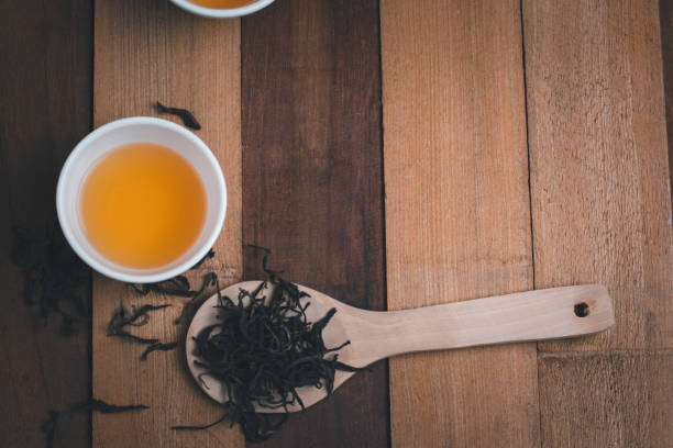 istock A tea cup with dry tea on the spoon and wooden background 1299186324