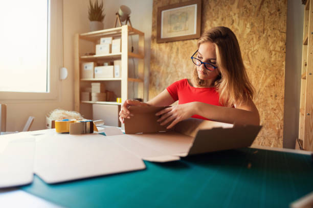 istock Young female small business owner is assembling cardboard box 1299192184