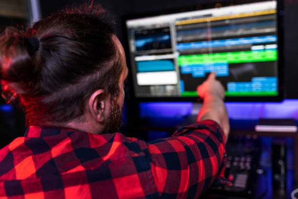 istock Young DJ man is showing on the computer in recording program what the idea he wants to add in his new song 1299192971