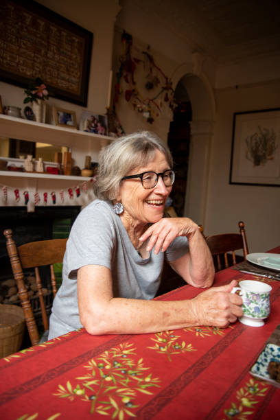 istock Older woman enjoys a laugh over morning tea. 1299197553