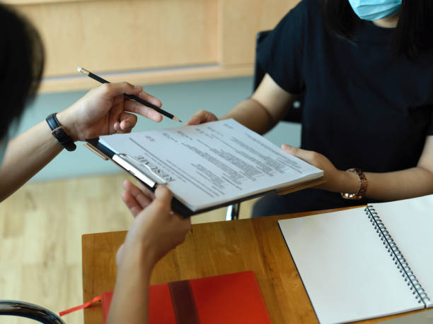 istock Two office worker working together with paperwork on clipboard in office room 1299198495