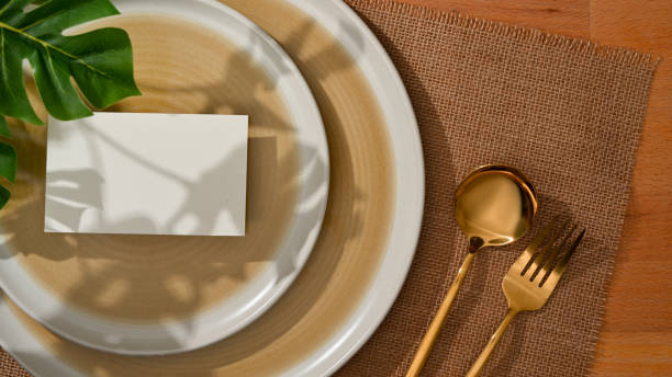 istock Dining set with mock up name card on mock up ceramic plate and brass spoon and fork 1299198556