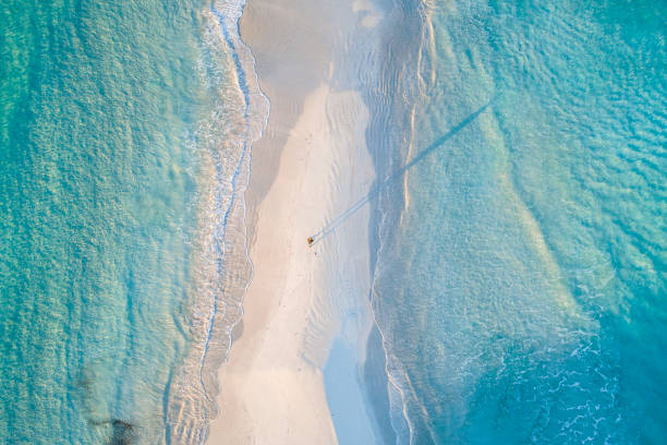 Picturesque coastline aerial photograph of aquamarine ocean and man walking along white sandbar beach Picturesque coastline aerial photograph of aquamarine ocean and man walking along white sandbar beach in Australia sandbar stock pictures, royalty-free photos & images