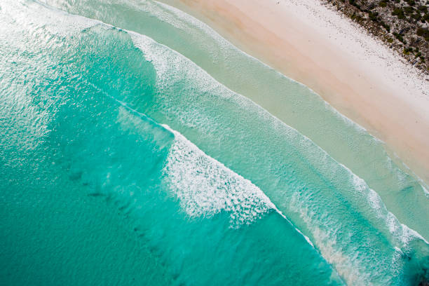 istock Clean ocean waves breaking on white sand beach with turquoise emerald coloured water 1299198714