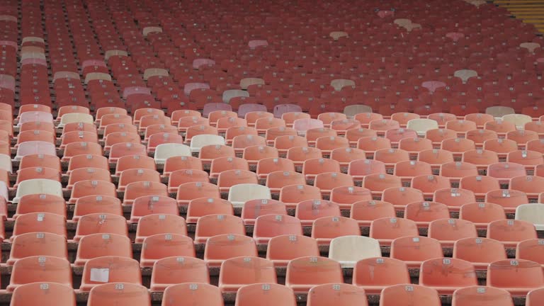 Red empty plastic seats in a stadium in a row.