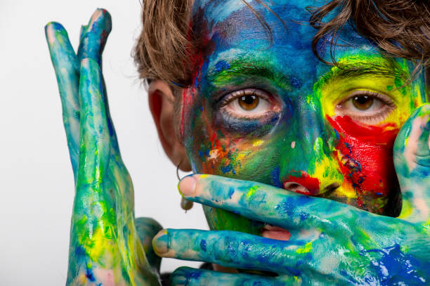 istock Teenage boy experiments with face/body paint in preparation for a school project. 1299202407