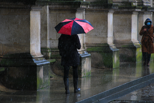 Paris, France. January 24. 2021. People in the rain walking down the street with an umbrella.