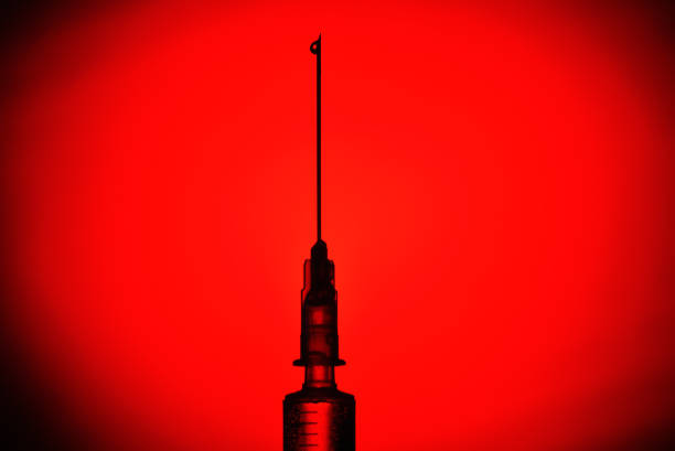 Medical Syringe with the Coronavirus vaccine on a red and black background on the lumen, silhouette. The concept of protection against Coronavirus infection, COVID-19 Medical Syringe with the Coronavirus vaccine on a red and black background on the lumen, silhouette. The concept of protection against Coronavirus infection, COVID-19 medical injection photos stock pictures, royalty-free photos & images
