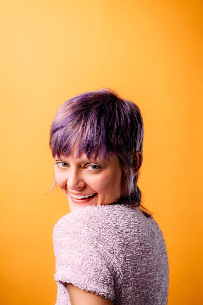 Studio Portrait of a Fashionable, Confident, Beautiful Person on a Mustard-Yellow Background with Copy Space Studio Portrait of a Fashionable, Confident, Beautiful Non-Binary Genderqueer Person with a Short Purple Pixie Haircut on a Mustard-Yellow Background purple hair stock pictures, royalty-free photos & images