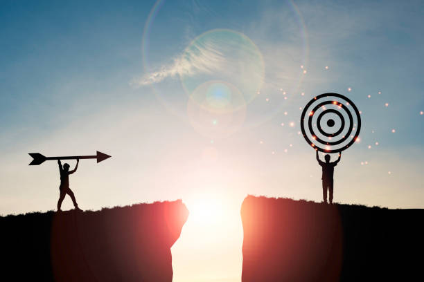 istock Silhouette men throwing arrow and holding dartboard on mountain with blue sky and sunlight for achievement objectives target concept. 1299219204