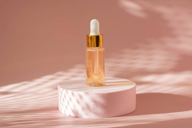 gold beauty serum in a pipette bottle on a pink podium with shadows gold beauty serum in a pipette bottle on a pink podium with shadows on a coral pink background beauty product photography stock pictures, royalty-free photos & images