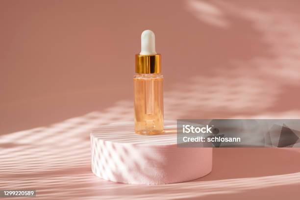 Gold Beauty Serum In A Pipette Bottle On A Pink Podium With Shadows Stock Photo - Download Image Now