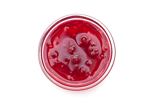 Raspberry jam in glass bowl, liquid jam isolated on white, top view, lay out with space for text
