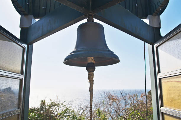 Church bell on church tower on blue sky background. Catholic church building. Catholic religious architecture detail. White stone tower with bell. Traditional religious building on tropical island