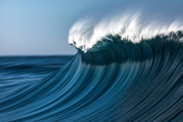 istock Large blue cresting wave breaking in the open ocean on a sunny day 1299224479