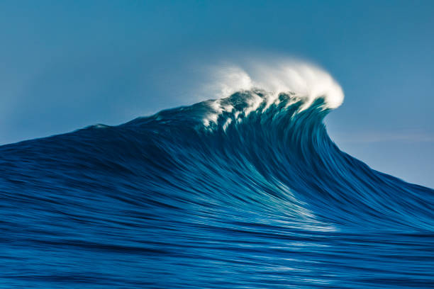 Large blue cresting wave breaking in the open ocean on a sunny day