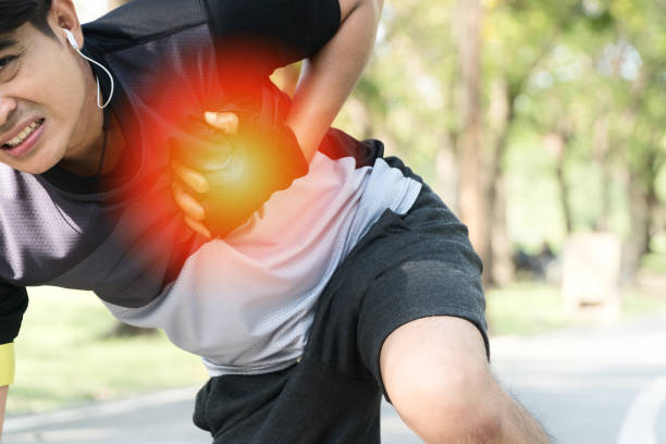 istock Injury concept. Attractive man suffering chest pain while jogging exercise in public park. 1299226654