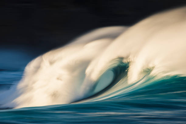 istock Cresting wave breaking with strong wind spray in the golden morning light 1299226686