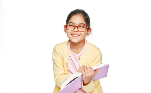 Beautiful multi-ethnic girl wearing eyeglasses holds book in her hands and laughs, looking at the camera Beautiful multi-ethnic girl wearing eyeglasses holds book in her hands and laughs, looking at the camera reading glasses stock pictures, royalty-free photos & images