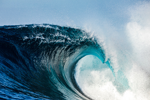 Powerful blue breaking wave breaking in the open ocean on a sunny day