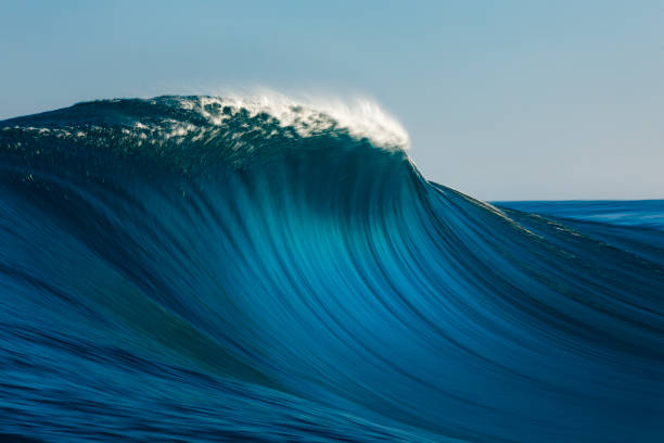 istock Large blue smooth wave breaking in the open ocean on a sunny day 1299230027