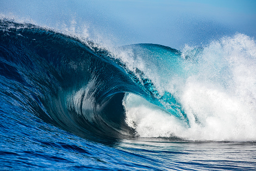 Powerful blue breaking wave breaking in the open ocean on a sunny day
