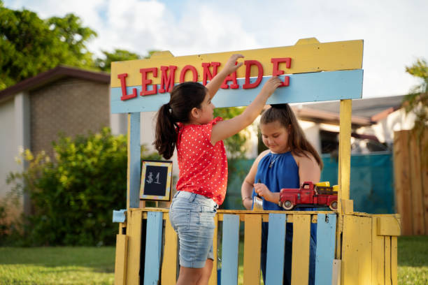 due ragazze ispaniche che mettono gli ultimi dettagli su di lei presto per essere aperto stand limonata - limonata foto e immagini stock