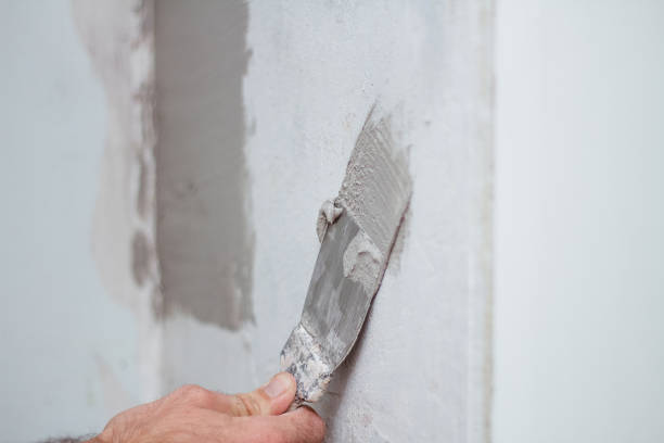istock man hand with trowel plastering a wall, skim coating plaster walls. 1299232413