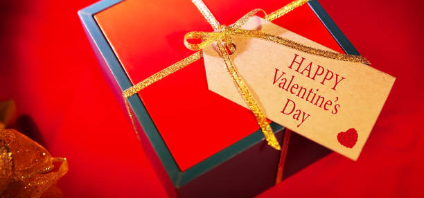 istock Label on a gift box with the text - happy Valentines day, red background, top view. 1299234019