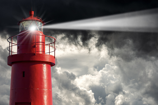 Closeup of an old Red Lighthouse with storm clouds on the background, bad weather.