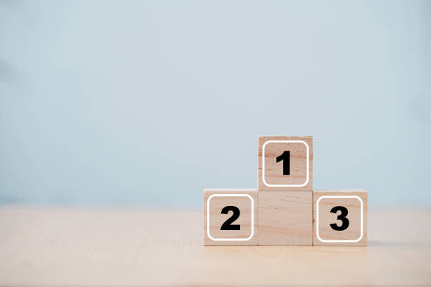 istock Number one two and tree print screen on wooden cube block for the winner runner-up and second runner-up of Award podium ceremony. 1299234982