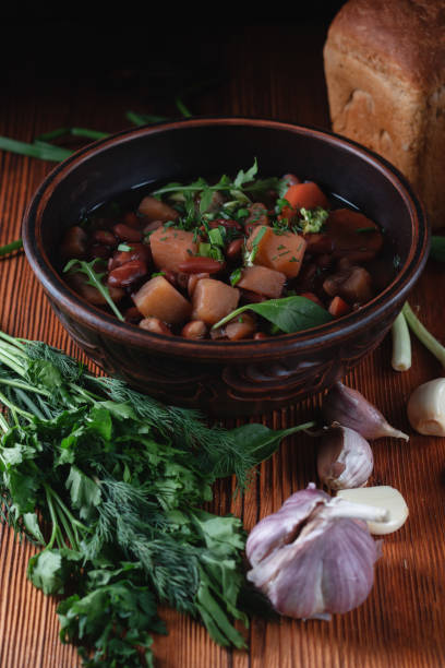 istock Bean soup with herbs in a clay bowl with fresh rye bread and garlic on a slate table on a dark background 1299235192