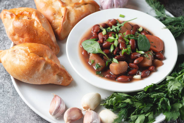 istock Bean soup with herbs in a white plate with fresh rye bread and garlic on a slate table on a dark background 1299235206