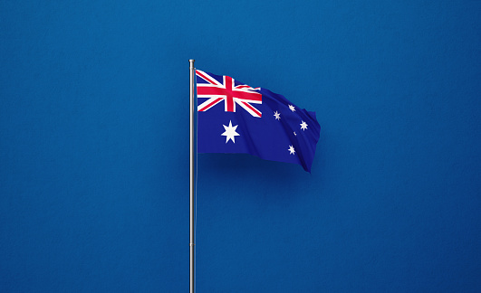 Australian flag attached to a flagpole  waving over navy blue background. Great use for Australian politics and Australian culture related concepts.