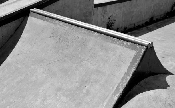 concrete skateboard playground in a fenced area outside the city. Railing ramps are for beginners on scooters, BMX bikes and skateboards. wavy areas for testing jumps and tricks active, balance, begin, bicycle, bike, bmx, board, boarding, child, children, concrete, cool, easy, empty, fence, halfpipe, jump, kid, leisure, lifestyle, metal, monochrome, obstacles, outdoor, park, pipe, playground, pole, railing, ramp, recreation, ride, scooter, skate, skateboard, skateboarder, skateboarding, skatepark, skater, skating, slide, sport, street, stunt, summer, sun, teenage, trick, urban, young jump board stock pictures, royalty-free photos & images