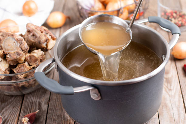 Saucepan with bouillon with a ladle on a wooden table. Bone broth Saucepan with bouillon with a ladle on the table. Bone broth amino acid photos stock pictures, royalty-free photos & images
