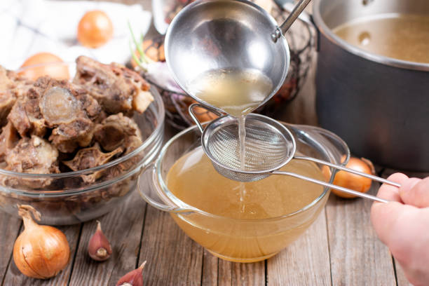 istock Passing the bone broth through a sieve. Concentrated Bone Broth in a bowl on the table 1299239474