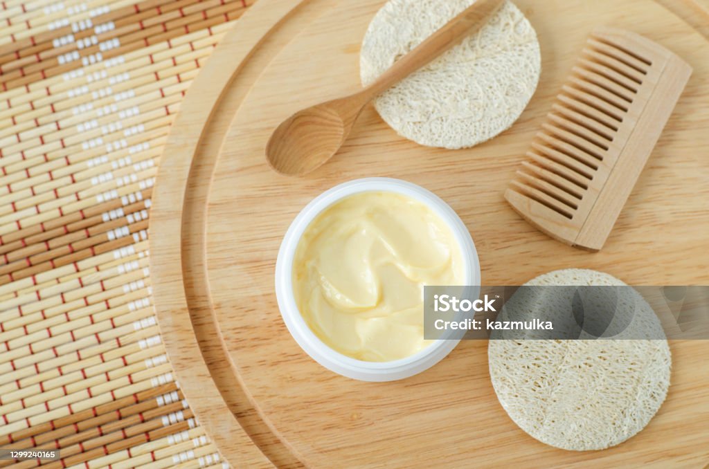 Yellow facial mask (banana face cream, shea butter hair mask, body butter) in the small white container. Natural skin and hair concept. Top view, copy space. Hair Treatment Stock Photo